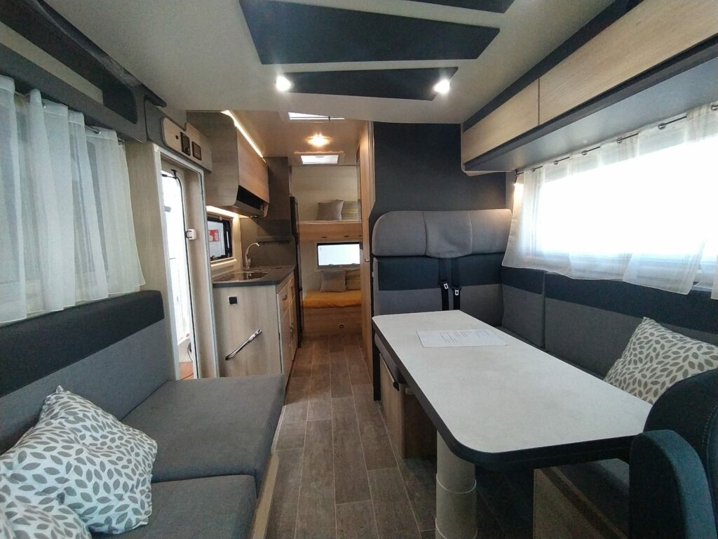 Interior de la autocaravana ITINEO PS700 2024, mostrando salón, cocina y literas traseras