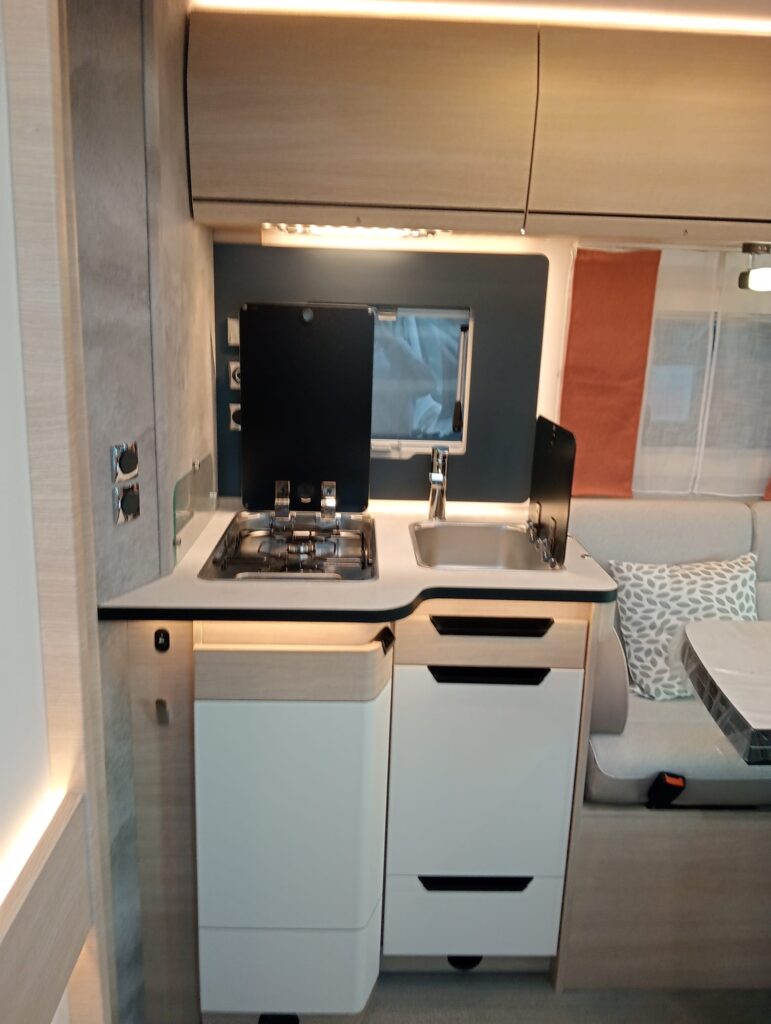 Cocina del Rapido C86 i cómoda y práctica con cristal protector, protección en la ventana, cerraduras automáticas en armarios y cajones, y luz sobre los fuegos.