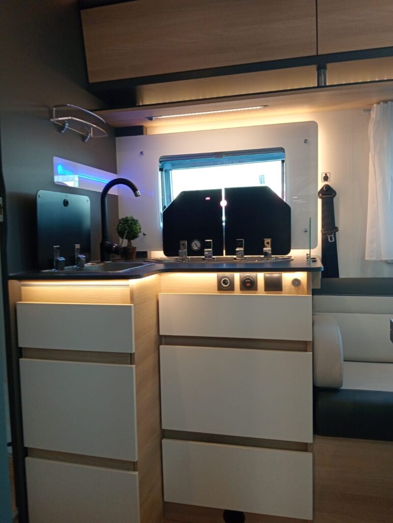 "Cocina amplia de la Itineo MC 740 Spirit Edition con dos fuegos, fregadero con extensión, armarios y cajones que se bloquean automáticamente para la conducción"