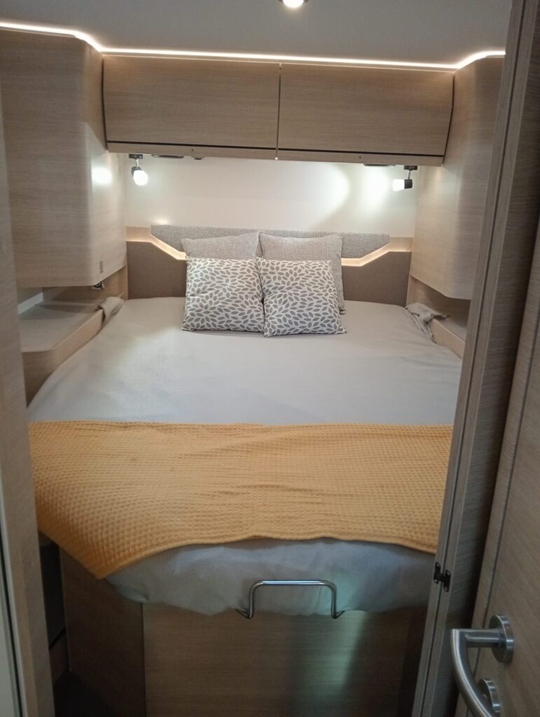 Habitación del Rapido C86 i con gran cama isla accesible por ambos lados, armarios de almacenamiento y puerta corredera que proporciona intimidad y aislamiento.