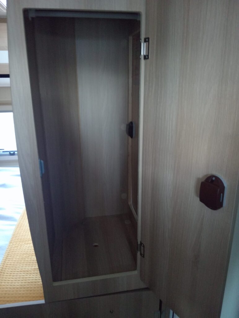 Armario de baño Dreamer D55 Saphir Select con acceso interior oculto y puerta cerrada, integrado en el diseño del baño de la furgoneta camper