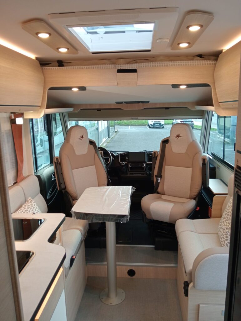 Interior del Rapido C86 i con salón amplio face-to-face, mesa en libro, asientos giratorios y cama hacia la cabina sin afectar el espacio del salón.