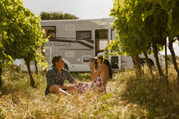 Feria de la Autocaravana de Biarritz 2026: pareja en prado con autocaravana al fondo (Caravanas Evasión)